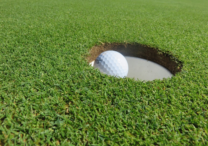 Close-up of golf ball going in a hole